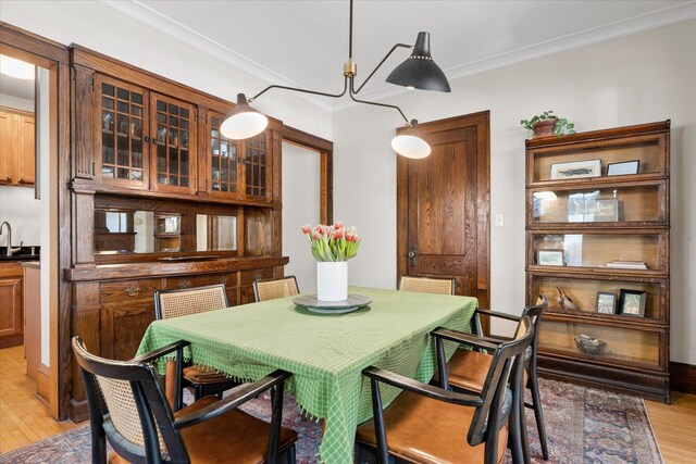 dining space with light wood-style flooring and ornamental molding