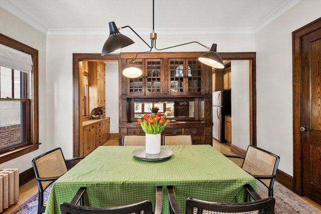 dining room featuring light wood-type flooring, baseboards, radiator heating unit, and crown molding