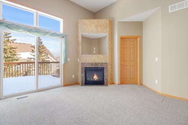 unfurnished living room with visible vents, a tile fireplace, baseboards, and carpet