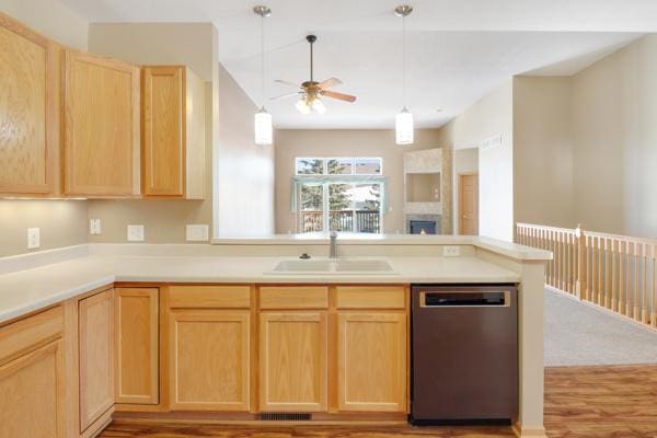 kitchen featuring a ceiling fan, light brown cabinets, a peninsula, a sink, and stainless steel dishwasher