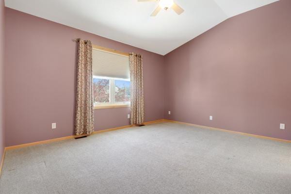 unfurnished room with baseboards, light carpet, and vaulted ceiling