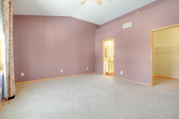 unfurnished bedroom featuring a spacious closet, a ceiling fan, lofted ceiling, and carpet floors