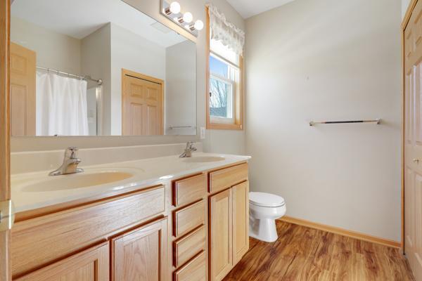 full bathroom with double vanity, toilet, wood finished floors, and a sink