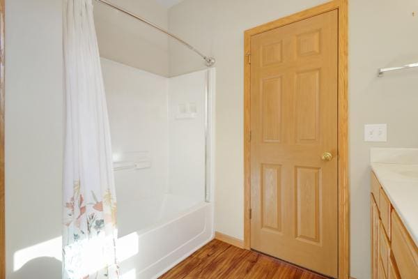 bathroom with vanity, shower / bath combination with curtain, and wood finished floors