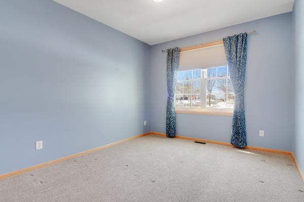 carpeted spare room with visible vents and baseboards