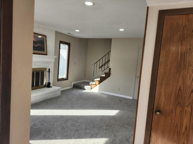 unfurnished living room with stairway, a brick fireplace, carpet flooring, and baseboards