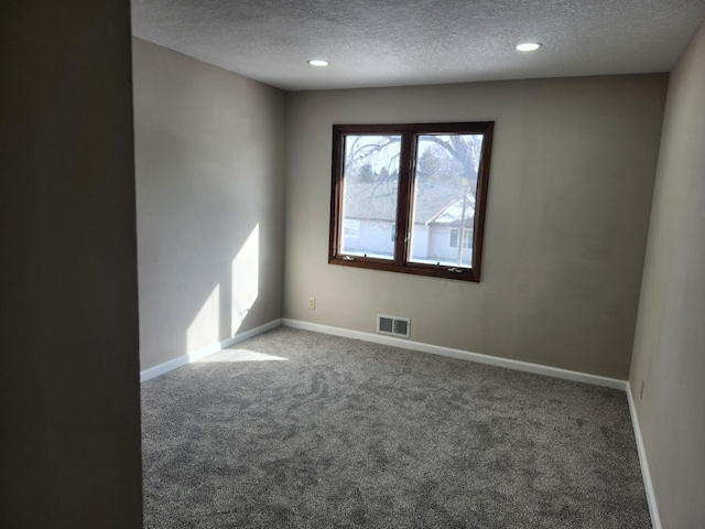 empty room with visible vents, a textured ceiling, baseboards, and carpet