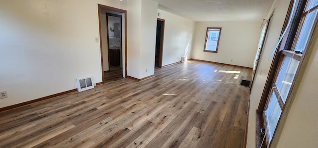 empty room with visible vents, baseboards, and wood finished floors