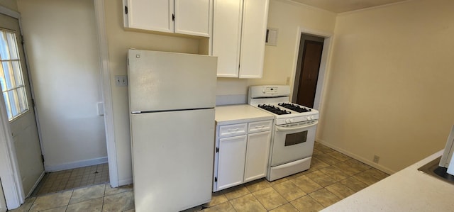 kitchen with baseboards, light countertops, light tile patterned floors, white cabinets, and white appliances