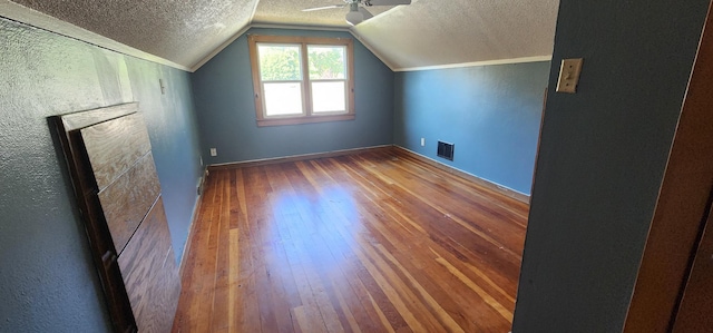 bonus room featuring visible vents, ceiling fan, vaulted ceiling, hardwood / wood-style flooring, and a textured ceiling