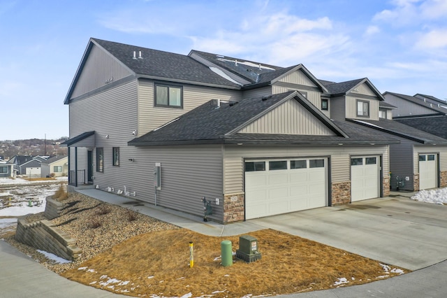 view of side of property featuring a residential view, driveway, roof with shingles, and an attached garage