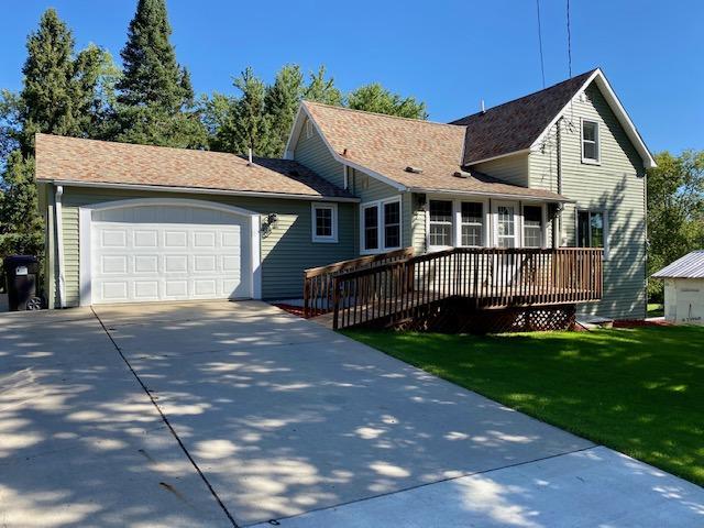 view of front facade with a deck, an attached garage, concrete driveway, and a front yard