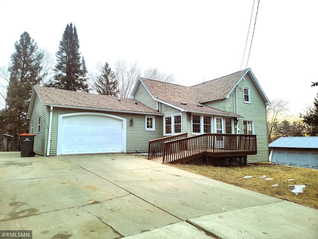 view of front of property with driveway, a deck, an attached garage, and a shingled roof