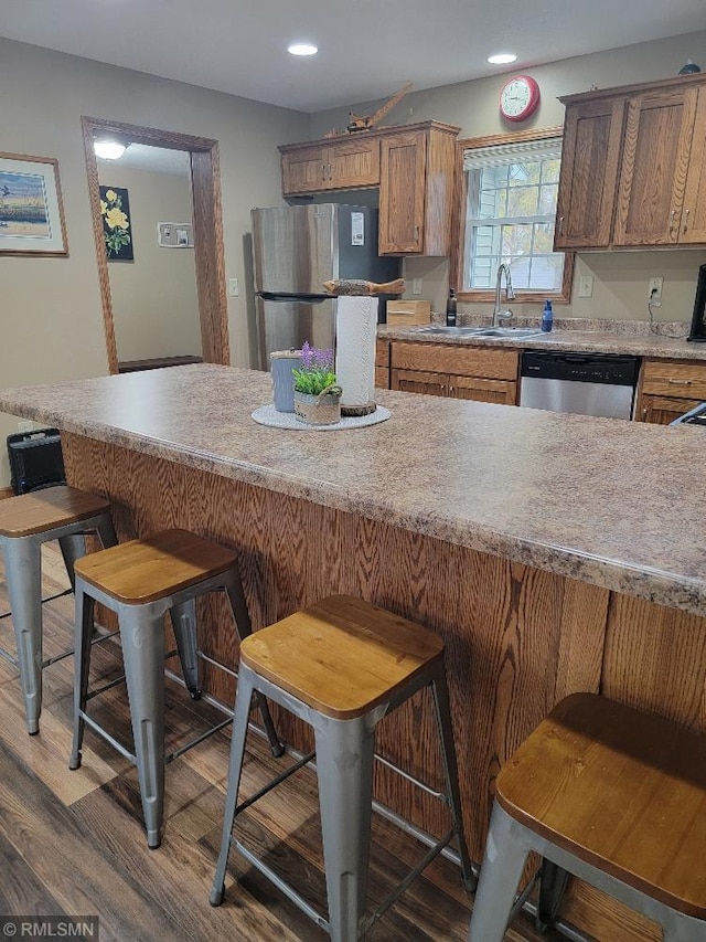 kitchen featuring a breakfast bar area, wood finished floors, recessed lighting, stainless steel appliances, and light countertops