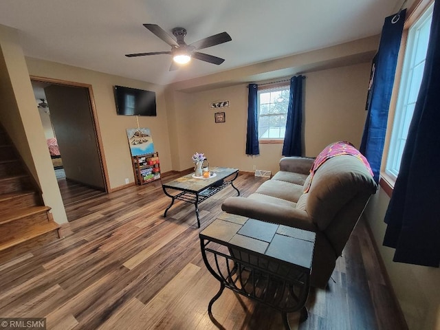 living area featuring a ceiling fan, stairway, wood finished floors, and baseboards