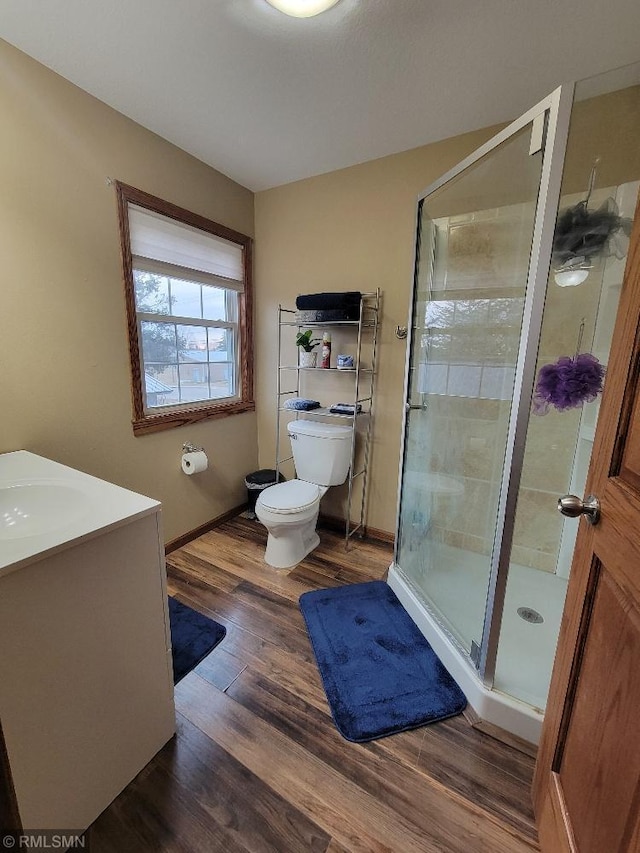 bathroom featuring a sink, a shower stall, toilet, and wood finished floors