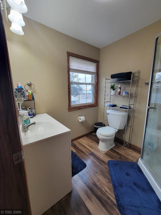 full bathroom with vanity, wood finished floors, baseboards, a stall shower, and toilet