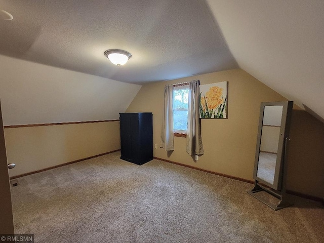 bonus room featuring baseboards, carpet flooring, a textured ceiling, and lofted ceiling