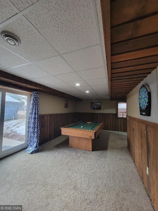 recreation room featuring a drop ceiling, light carpet, wood walls, and wainscoting