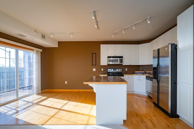 kitchen featuring visible vents, light wood-style flooring, a kitchen island, white cabinetry, and stainless steel appliances