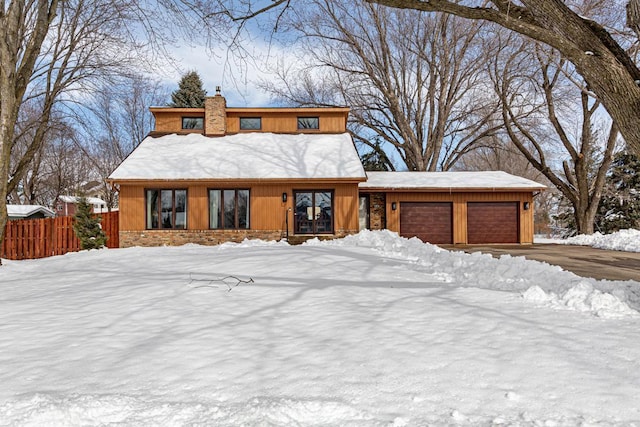 view of front of property featuring an attached garage, a chimney, and fence