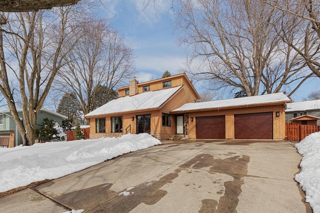 view of front of home with fence, a chimney, concrete driveway, a garage, and board and batten siding