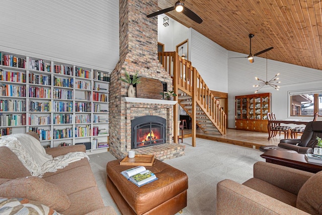 carpeted living area with high vaulted ceiling, ceiling fan with notable chandelier, wooden ceiling, a fireplace, and stairs