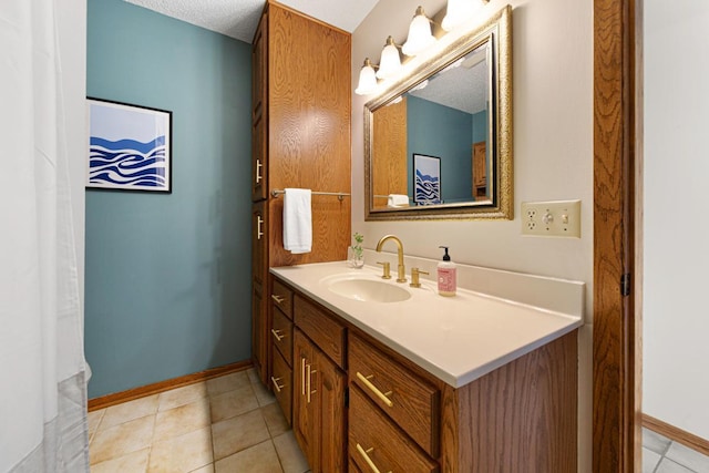 bathroom with tile patterned floors, baseboards, a textured ceiling, and vanity