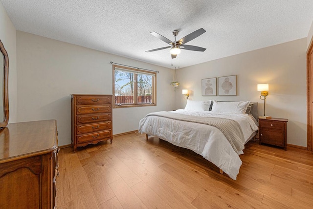 bedroom featuring light wood finished floors, baseboards, a textured ceiling, and a ceiling fan