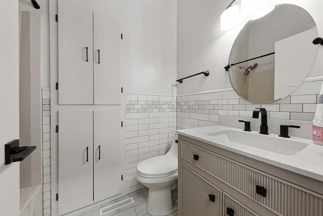 bathroom featuring vanity, visible vents, a shower, tile walls, and toilet