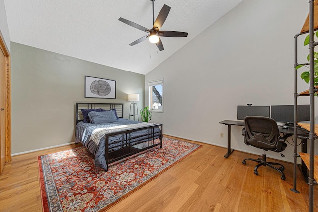 bedroom featuring a textured ceiling, high vaulted ceiling, baseboards, and wood finished floors