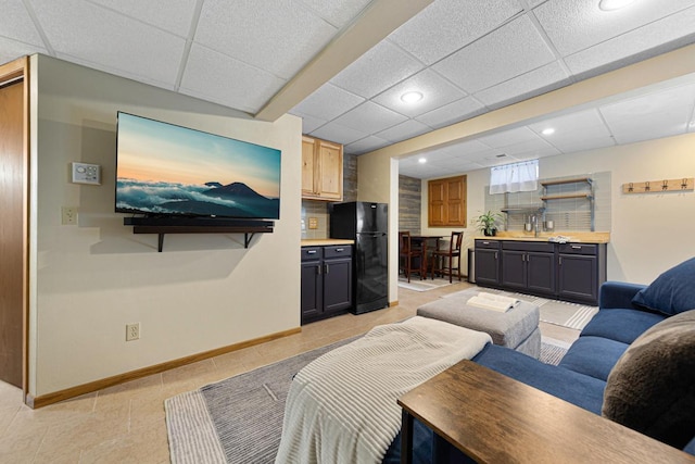 living room with recessed lighting, a paneled ceiling, and baseboards