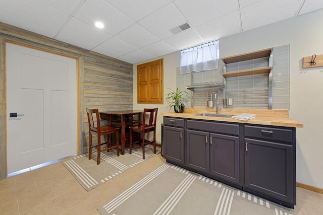 kitchen with visible vents, open shelves, a drop ceiling, butcher block countertops, and a sink