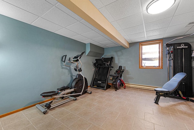 workout area featuring a drop ceiling, baseboard heating, and baseboards