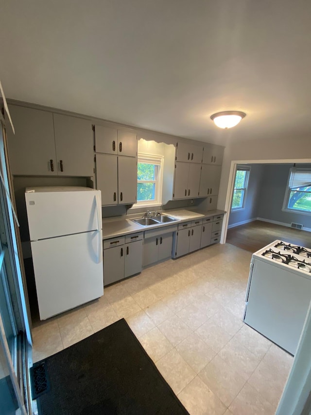 kitchen with visible vents, gray cabinets, white appliances, and a sink