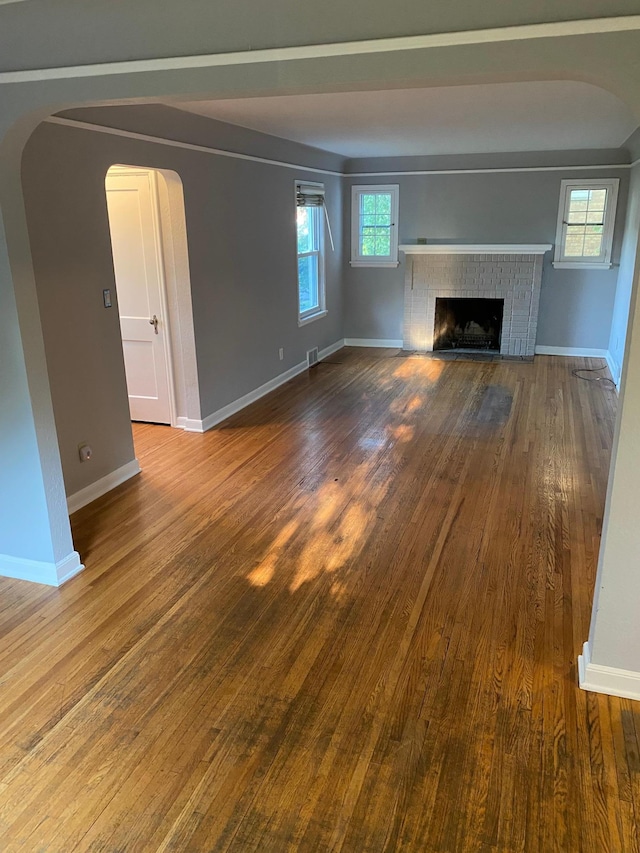 unfurnished living room with visible vents, a fireplace, baseboards, and wood finished floors