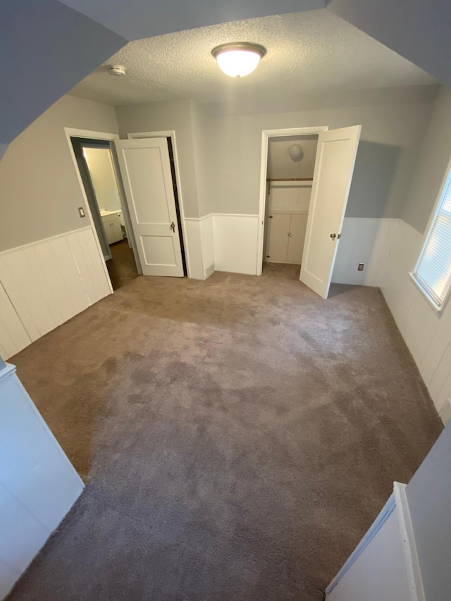 unfurnished bedroom with carpet, wainscoting, and a textured ceiling