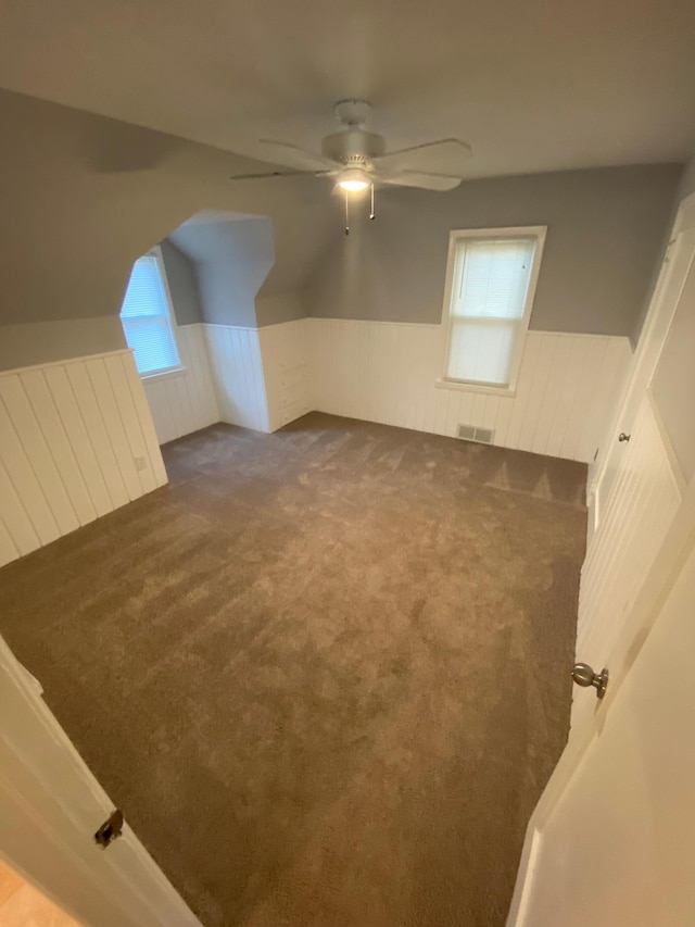 bonus room with a wainscoted wall, carpet flooring, visible vents, and ceiling fan