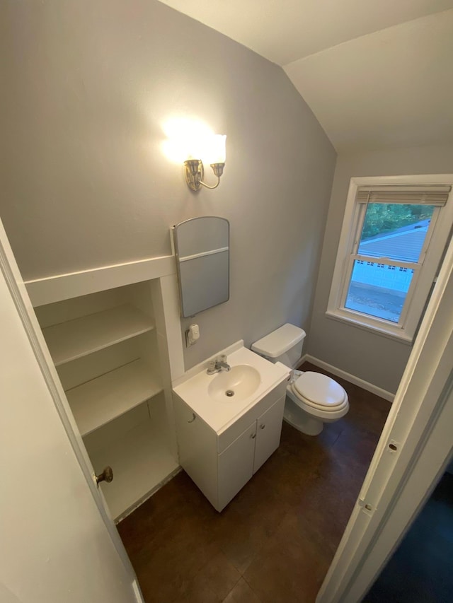 bathroom with toilet, vanity, and vaulted ceiling