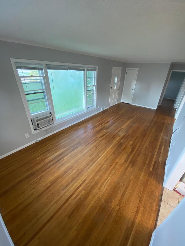 unfurnished living room with cooling unit, plenty of natural light, and wood finished floors