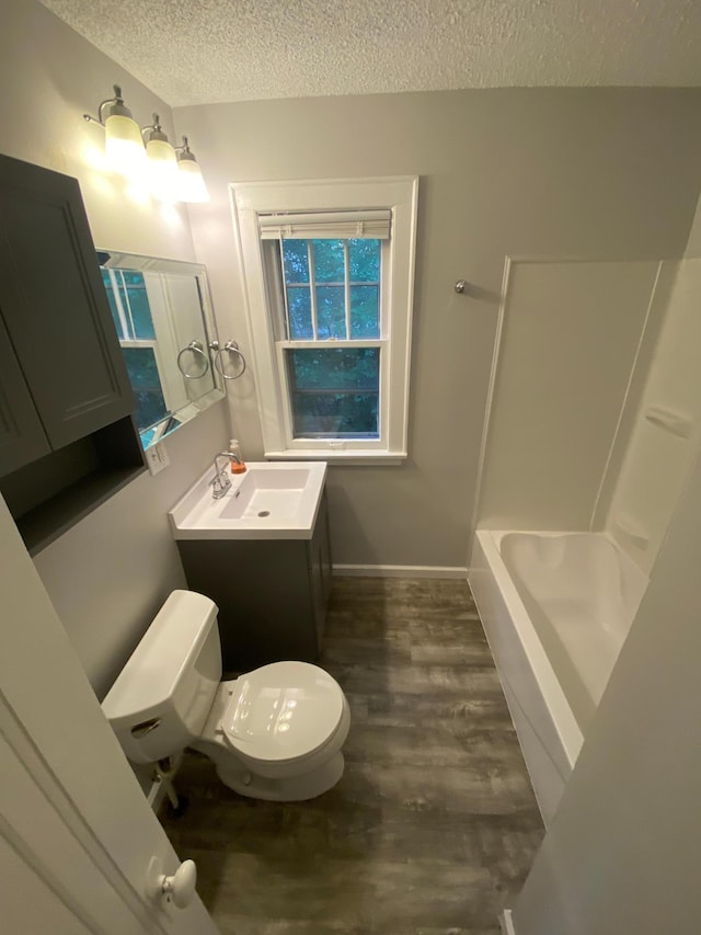 bathroom featuring vanity, wood finished floors, baseboards, a textured ceiling, and toilet