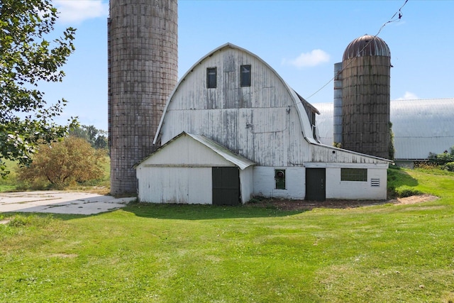 rear view of house featuring an outbuilding, a barn, a gambrel roof, and a yard