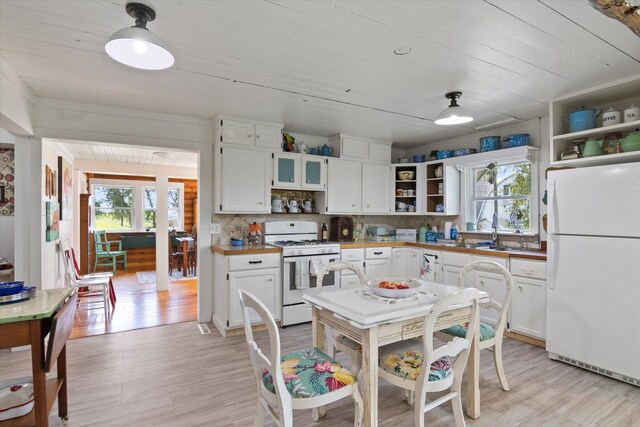 kitchen with white appliances, white cabinets, open shelves, and a sink