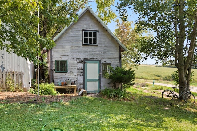 rear view of house featuring a lawn and an outdoor structure