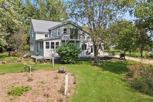 view of front of house with a wooden deck, a balcony, metal roof, and a front yard