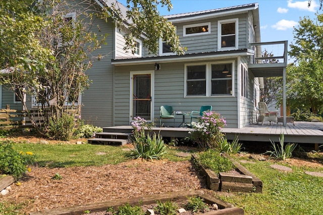 rear view of house featuring metal roof, a balcony, and a deck