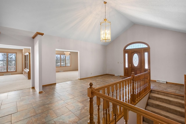 carpeted foyer entrance featuring visible vents, baseboards, stairway, an inviting chandelier, and stone finish floor