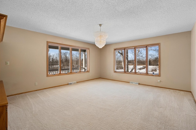 carpeted spare room with baseboards, visible vents, and a chandelier