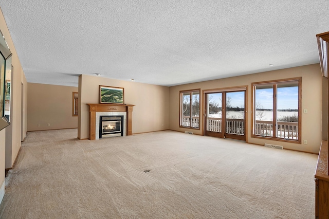 unfurnished living room featuring a fireplace, visible vents, carpet floors, and baseboards