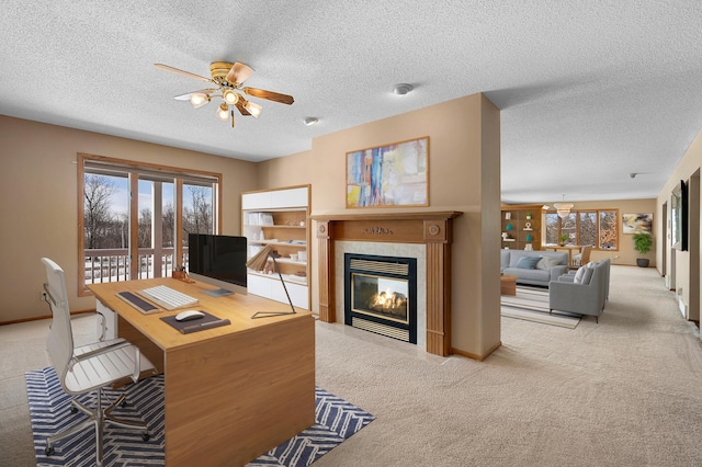 carpeted office with a wealth of natural light, baseboards, ceiling fan, and a fireplace